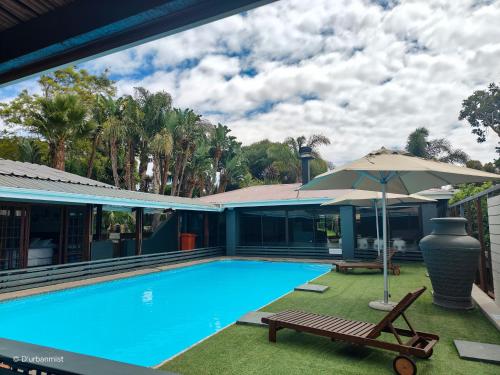 uma grande piscina com um guarda-sol e um banco em D'urbanmist em Durbanville