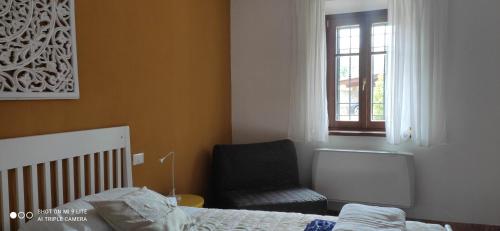 a bedroom with a bed and a chair and a window at Cintoia, Tuscany Beautiful villa with private pool in Santa Luce