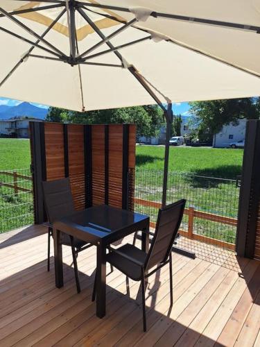 a table and chairs under an umbrella on a deck at Tiny House mit Sonnenterrasse in Lustenau