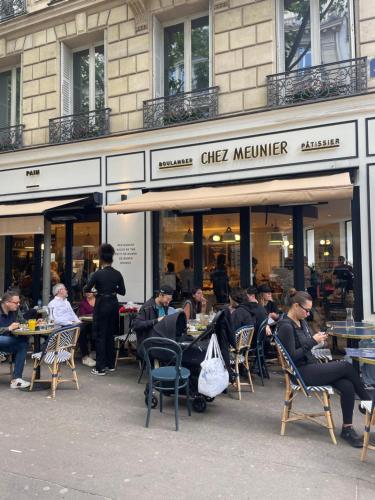 un grupo de personas sentadas en las mesas fuera de un restaurante en joli studio paris 16 Victor Hugo, en París