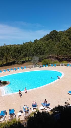 une grande piscine avec des chaises et des gens sur la plage dans l'établissement BISCARROSSE Appartement avec terrasse PISCINE LAC OCEAN GOLF, à Biscarrosse