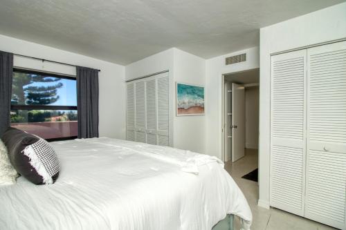 ein weißes Schlafzimmer mit einem großen Bett und einem Fenster in der Unterkunft Island Whispers Hideaway in Marco Island