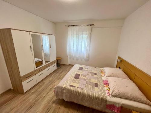 um quarto com uma cama, uma cómoda e um espelho em Apartmani Krunić em Barbat na Rabu