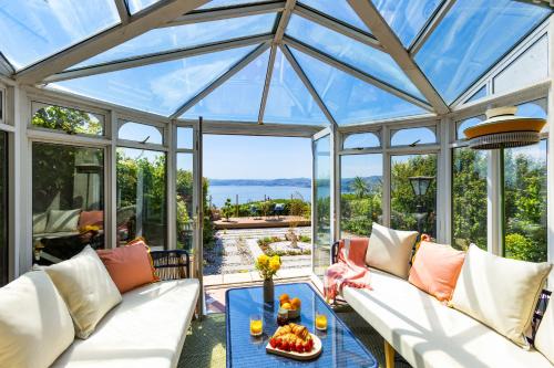 einen Wintergarten mit weißen Sofas und einem Tisch in der Unterkunft Vane Tower - Award winning designer retreat with panoramic sea views in Torquay