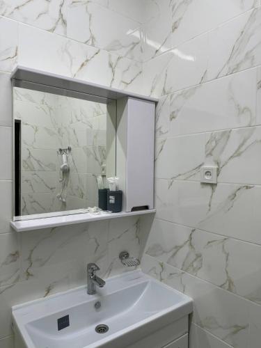 La salle de bains blanche est pourvue d'un lavabo et d'un miroir. dans l'établissement Айкол, à Bokonbayevo