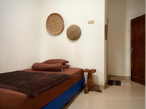 a bedroom with a bed and two hats on the wall at V & E Home Stay Cimaja Beach in Cimaja