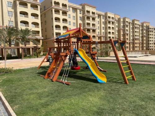 a playground with a slide in the grass with a building at 5 stars Studio Aqua View North coast in Borg El Arab