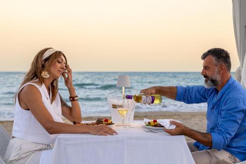 a man and woman sitting at a table drinking wine at Hotel Negresco in Lido di Jesolo