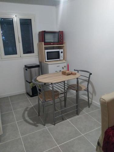 une cuisine avec une table avec des chaises et un micro-ondes dans l'établissement La Petite Maisonnette des Amoureux, à Chitray