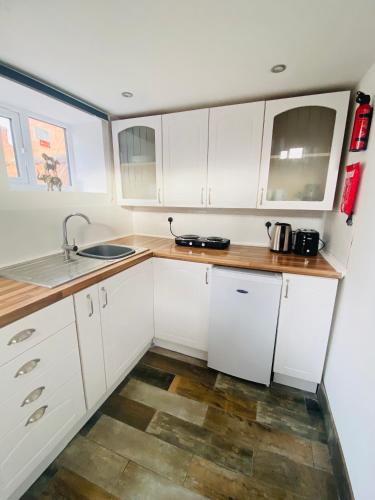 a kitchen with white cabinets and a sink at Cosy Cart Shed in Evesham