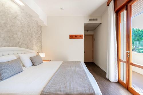 a bedroom with a large white bed and a window at Hotel Negresco in Lido di Jesolo
