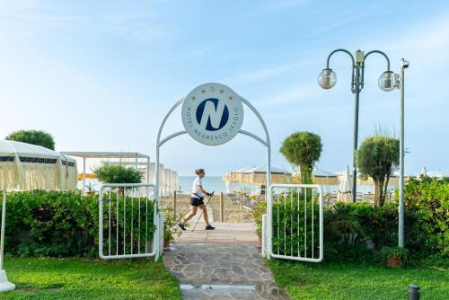 a woman walking through a gate in a garden at Hotel Negresco in Lido di Jesolo