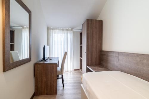 a bedroom with a bed and a desk with a mirror at Hotel Negresco in Lido di Jesolo