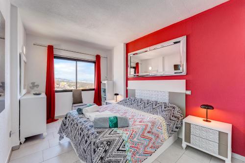 a bedroom with a red accent wall and a bed at 14th floor Sea View in Adeje