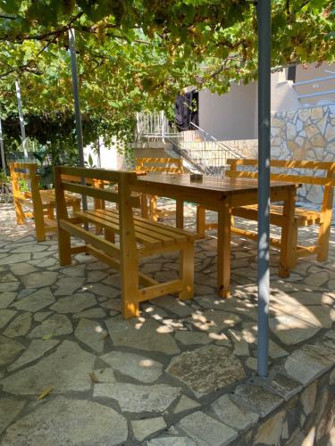 a wooden picnic table and bench under a tree at Vila Rapo in Himare