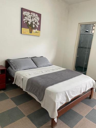 uma cama num quarto com uma fotografia na parede em Suíte Família para até 4 pessoas em casa de praia em Bertioga