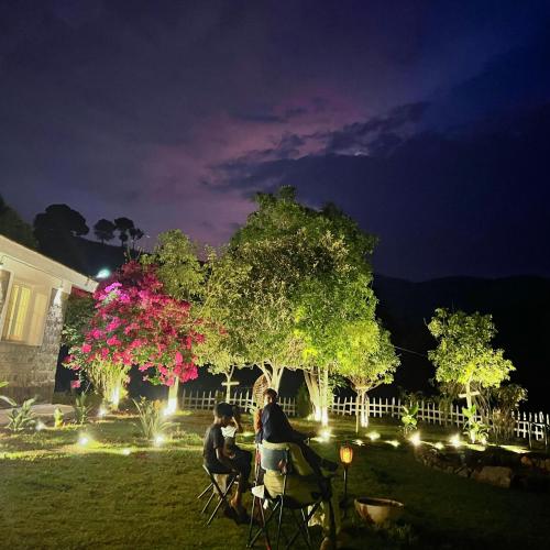 two people sitting at a table in a yard at night at Earth songs by Green leaves - 10 kms from kotagiri in Kotagiri