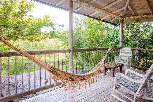 a hammock on a porch with two chairs and a table at Hotel Playa Manglares Isla Baru in Baru