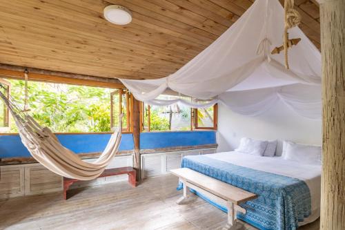 a bedroom with a hammock and a bed and windows at Hotel Playa Manglares Isla Baru in Baru