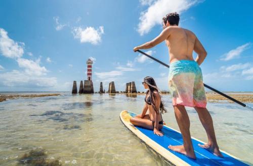 a man and a woman on a paddle board in the water at Pousada Maré Alta in Maceió