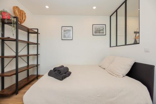 - une chambre avec un lit blanc et une étagère dans l'établissement Ma parenthèse, à Wimereux