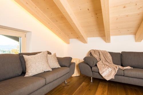 two couches in a living room with wooden ceilings at Gasthof Hubertus in Saalfelden am Steinernen Meer
