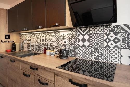 - une cuisine avec un évier et un mur en carrelage dans l'établissement Chez Sissi Appartement Cosy à Annecy Proche Centre, à Annecy