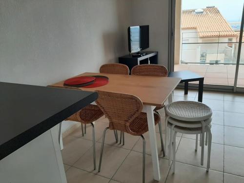 une table à manger avec des chaises et une télévision dans l'établissement Le Phare au cap Saint Clair, à Sète