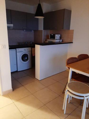 une cuisine avec une table et une machine à laver dans l'établissement Le Phare au cap Saint Clair, à Sète