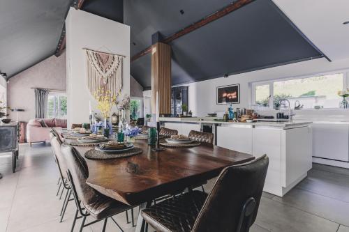 a kitchen and dining room with a wooden table and chairs at The Curlews - Waterside, boutique home with 10 person spa in Bishopsteignton