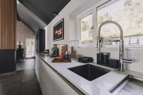 a kitchen counter with a sink and a window at The Curlews - Waterside, boutique home with 10 person spa in Bishopsteignton