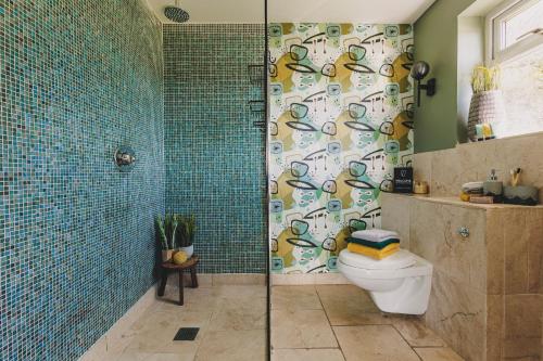 a bathroom with a shower with a toilet and a shower curtain at The Curlews - Waterside, boutique home with 10 person spa in Bishopsteignton