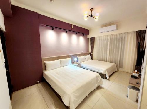 una habitación de hotel con 2 camas y una pantalla grande en 別有洞天包棟電梯民宿, en Taitung