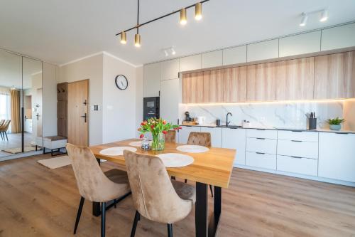 a kitchen and dining room with a wooden table and chairs at P R A T U M 17 Apartament z widokiem na jezioro in Mikołajki