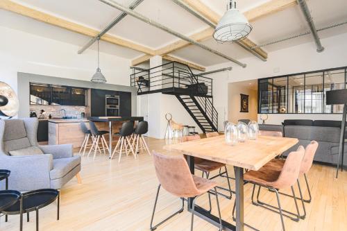 Il dispose d'une cuisine et d'un salon avec une table et des chaises en bois. dans l'établissement IKIZEN Prestige - Loft du Cadran - parking privé, à Reims