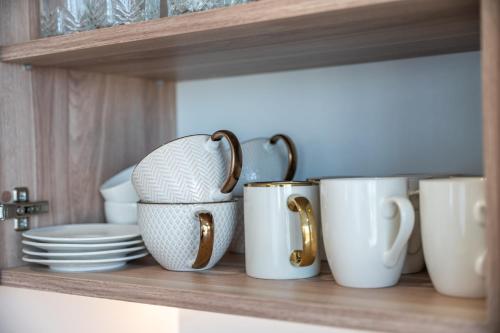 a shelf with coffee cups and plates on it at P R A T U M 17 Apartament z widokiem na jezioro in Mikołajki