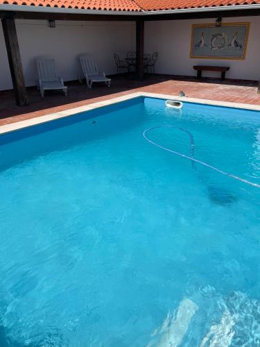 a large blue swimming pool with two chairs in it at Quinta das Palmeiras - Casa no Campo com Piscina in Pegões
