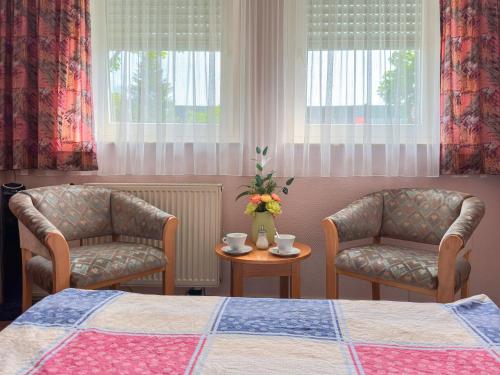a bedroom with two chairs and a bed and a table at Hotel DenRiKo in Heidelberg
