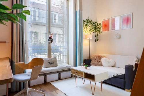 un salon avec un canapé et une fenêtre dans l'établissement Vivez Paris en famille - 3 chambres by 93 LaF, à Paris