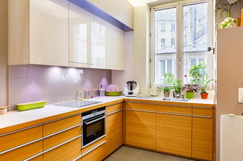 une cuisine avec des placards en bois et une grande fenêtre dans l'établissement Vivez Paris en famille - 3 chambres by 93 LaF, à Paris