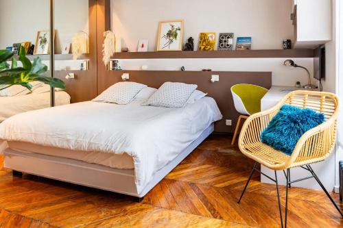 une chambre avec un grand lit et deux chaises dans l'établissement Vivez Paris en famille - 3 chambres by 93 LaF, à Paris