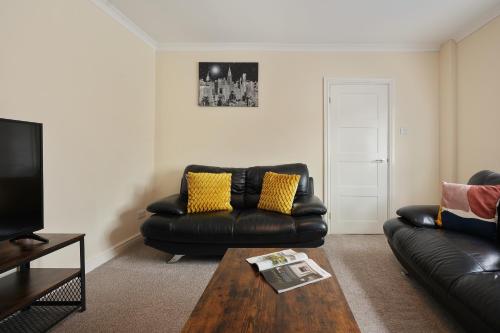 a living room with two leather couches and a coffee table at Exceptional 3 bed house with homely comforts, Close to fast food, supermarkets and city centre in Sheffield