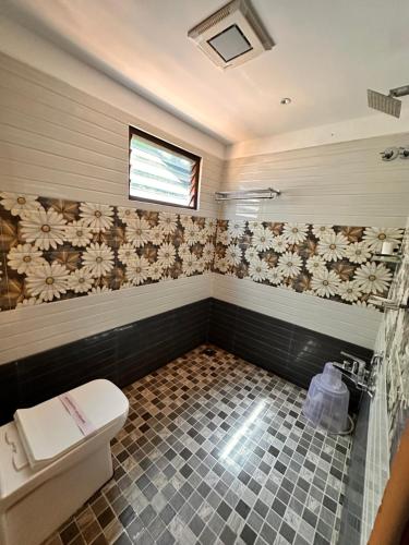 a bathroom with a toilet and flowers on the wall at Luxe Hotel Thekkady in Thekkady