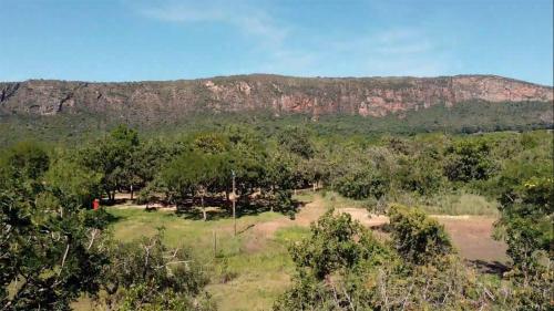 a field with trees and a mountain in the background at Cachoeiras Pé da Serra in São João Batista do Glória