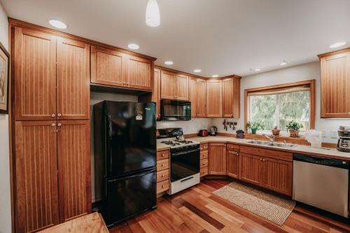 a kitchen with wooden cabinets and a black refrigerator at 77MBR - Wi-Fi - Fireplace - Pets Ok - BBQ cabin in Glacier