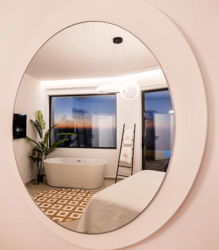 a mirror reflecting a bathroom with a tub and a sink at Aeliades Villas in Agios Nikitas