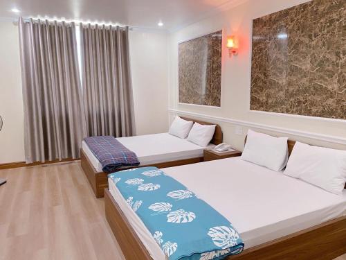 a hotel room with two beds and a window at Đình Vũ 3 MOTEL in Hai Phong