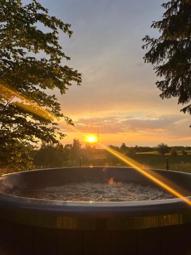 a hot tub with the sunset in the background at Domek Pod Świerkami in Sorkwity