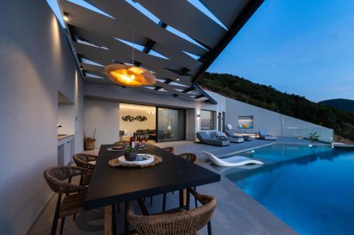a dining room with a table and chairs next to a swimming pool at Aeliades Villas in Agios Nikitas