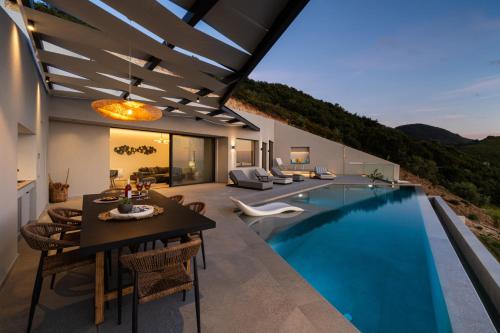 a house with a swimming pool with a dining table and chairs at Aeliades Villas in Agios Nikitas